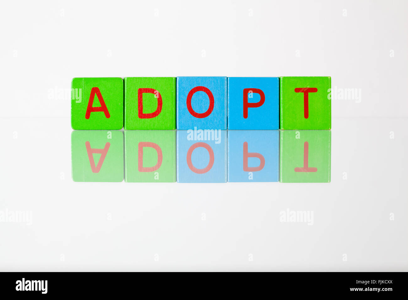 Adopt - an inscription from children's wooden blocks Stock Photo