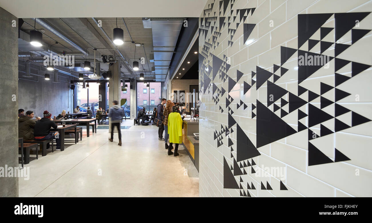 Lounge interior with graphics and tiled wall. MMU Student Union, Manchester, United Kingdom. Architect: Feilden Clegg Bradley St Stock Photo