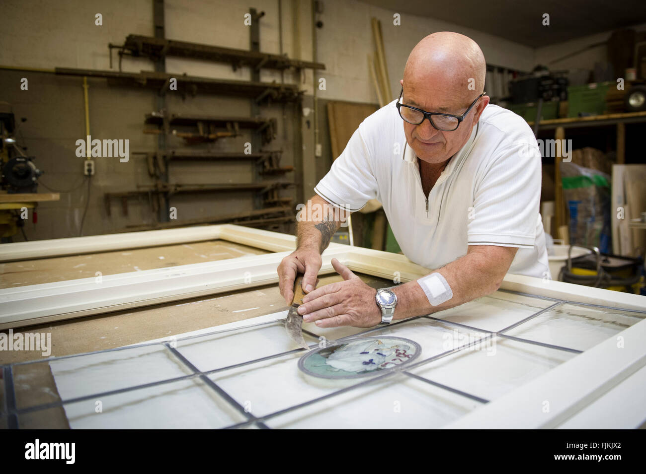 Photo: Gerrit de Heus. The Netherlands. The Hague. 01-02-2016. Older man working on stained glass window. Stock Photo