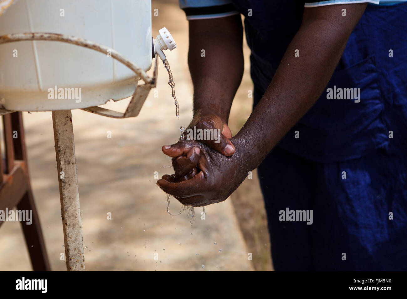 A man washing his hands from a home made tap, Tanzania. Stock Photo