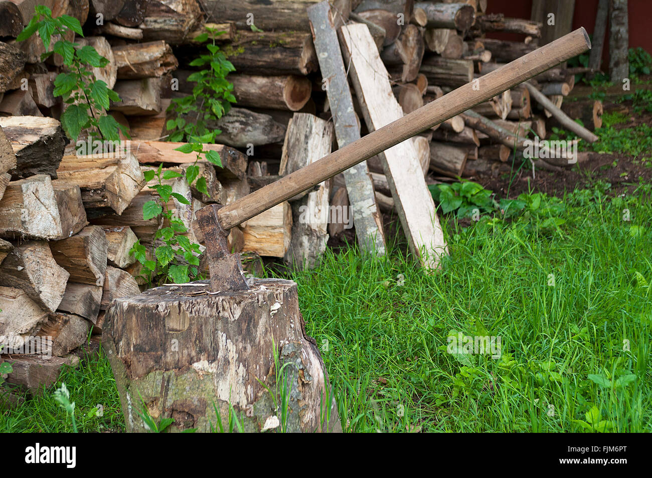 Axe stuck in a log. Pile of wood Stock Photo