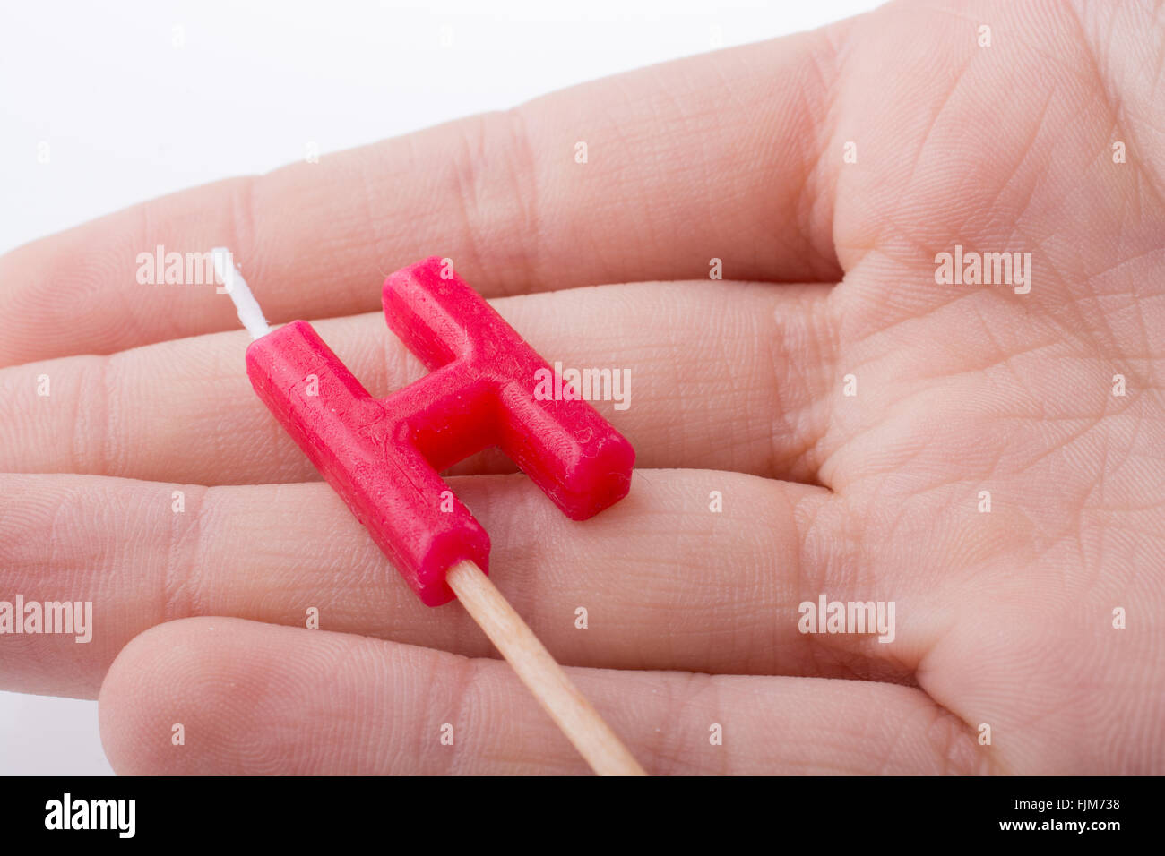 Color candle in hand on sticks writes the letter H Stock Photo - Alamy