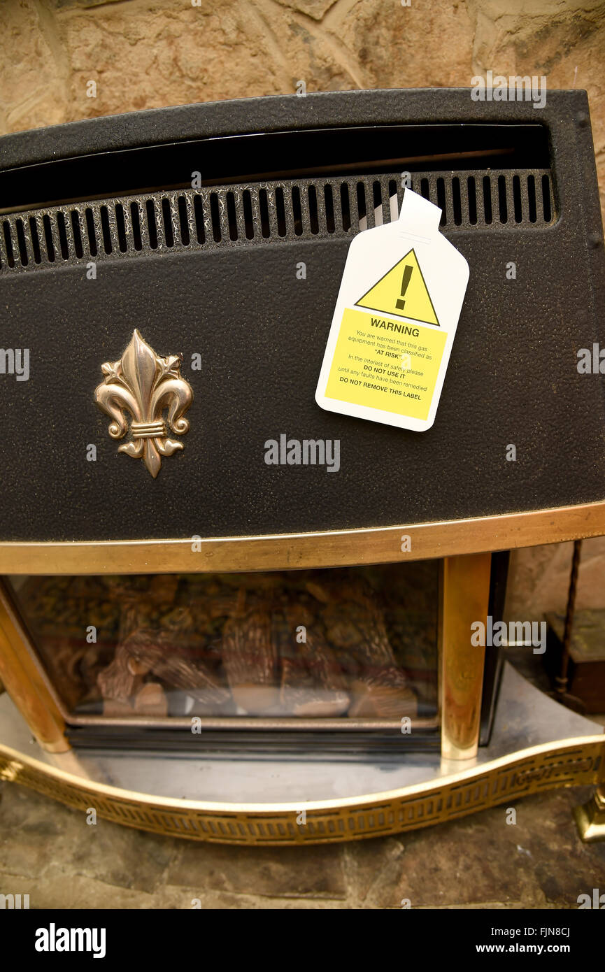 Unsafe gas fire, fireplace with warning sign, UK Stock Photo