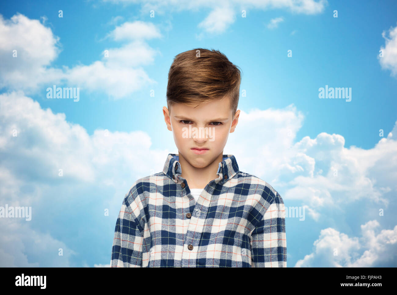 angry boy in checkered shirt over blue sky Stock Photo