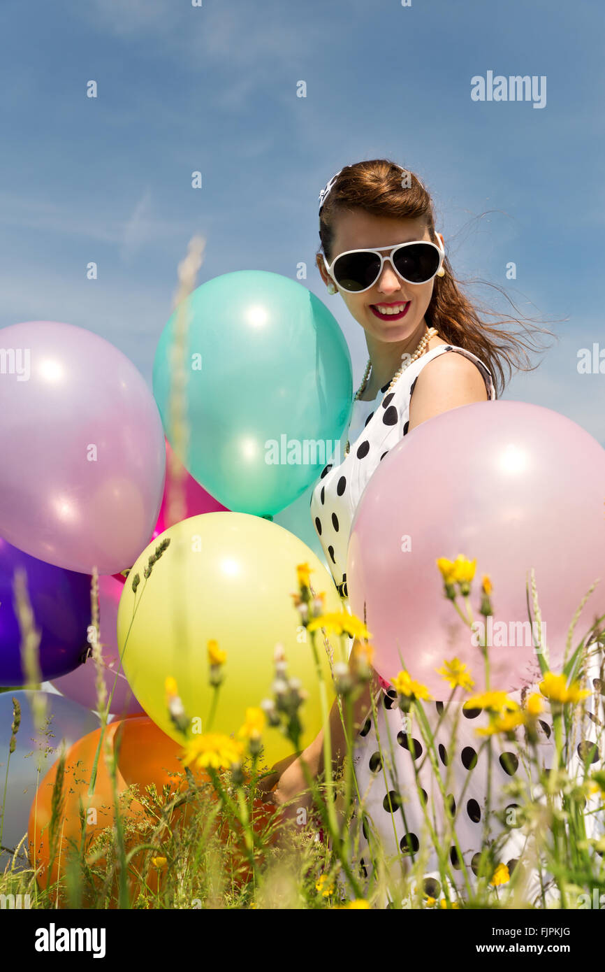 Attractive Rockabilly Girl with sunglasses and a suicide roll, a dotted  dress from the 50´s and balloons Stock Photo - Alamy