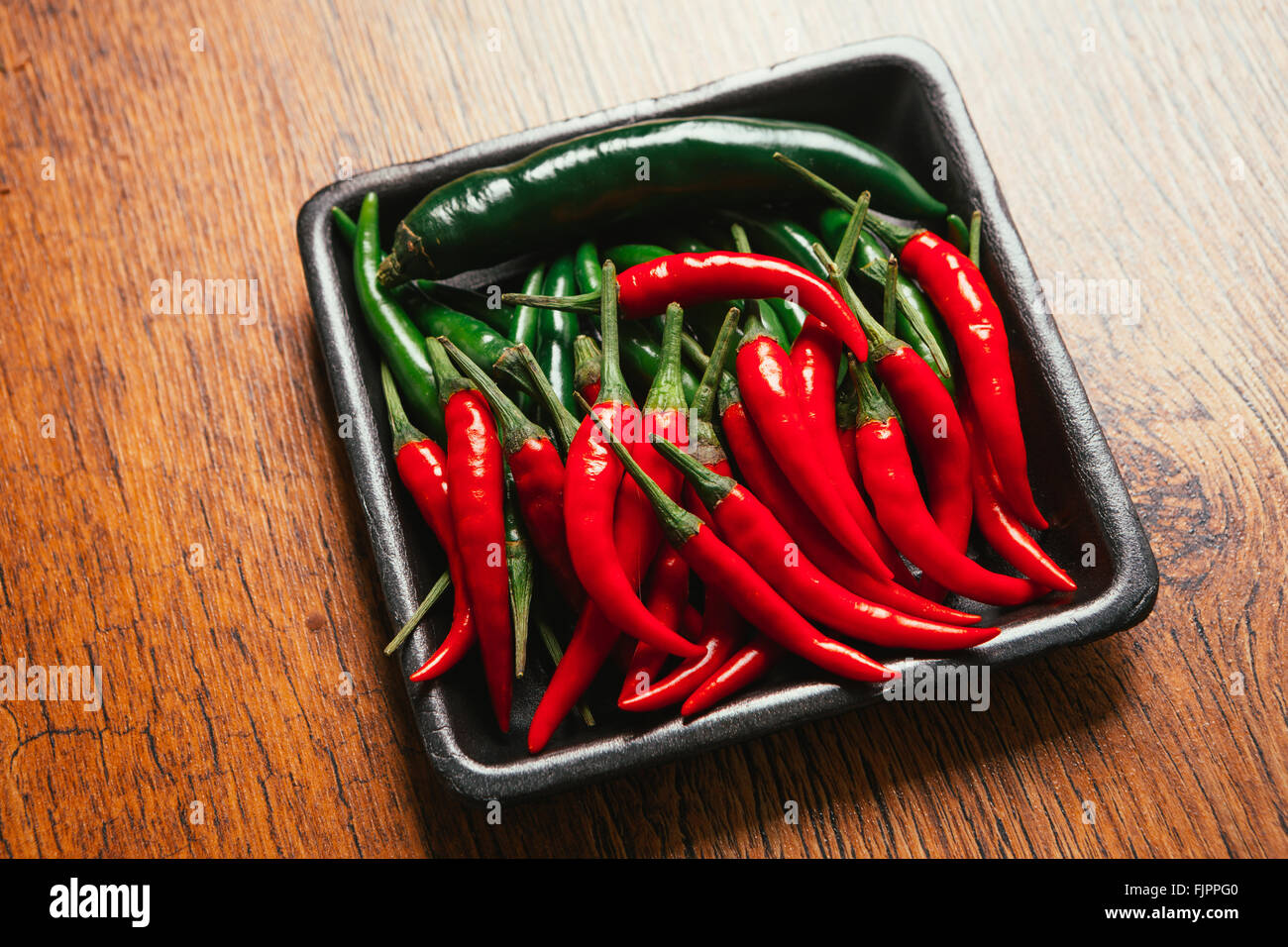 red and green chili peppers close up on wooden background Stock Photo ...