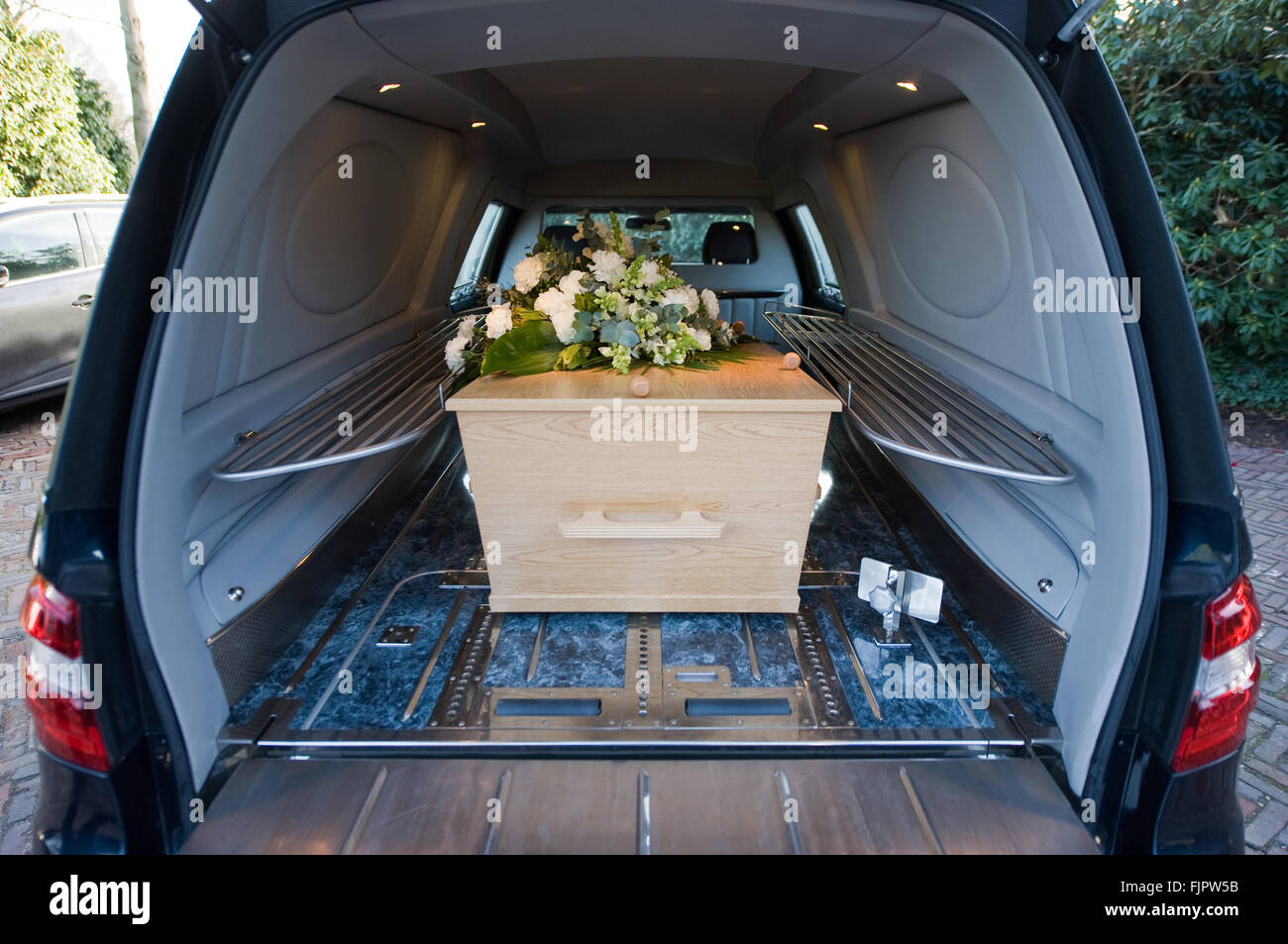 A coffin in a mourning car with a flower arrangement Stock Photo