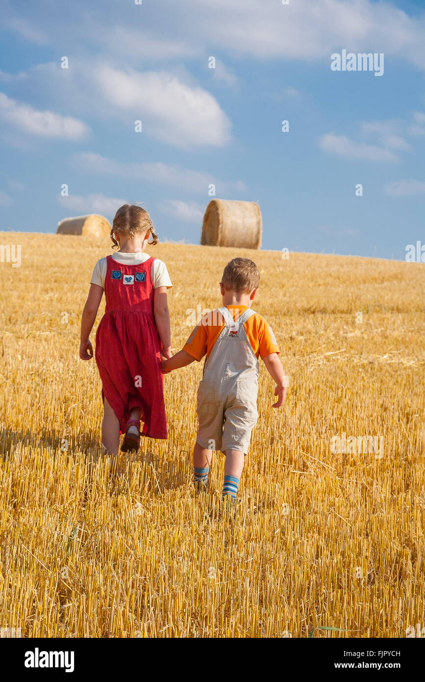 Girl and boy holding each other's hands and walking on a large stubble