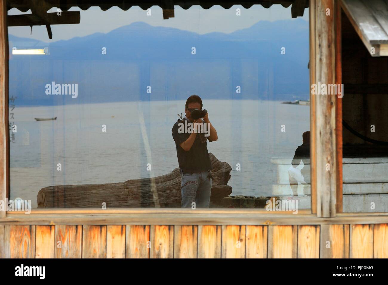 Man Photographing Self From Reflection On Glass Window Stock Photo