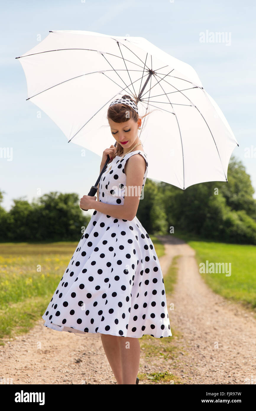 vintage fifties look with petticoat dress, hairband und sunshade in the nature Stock Photo