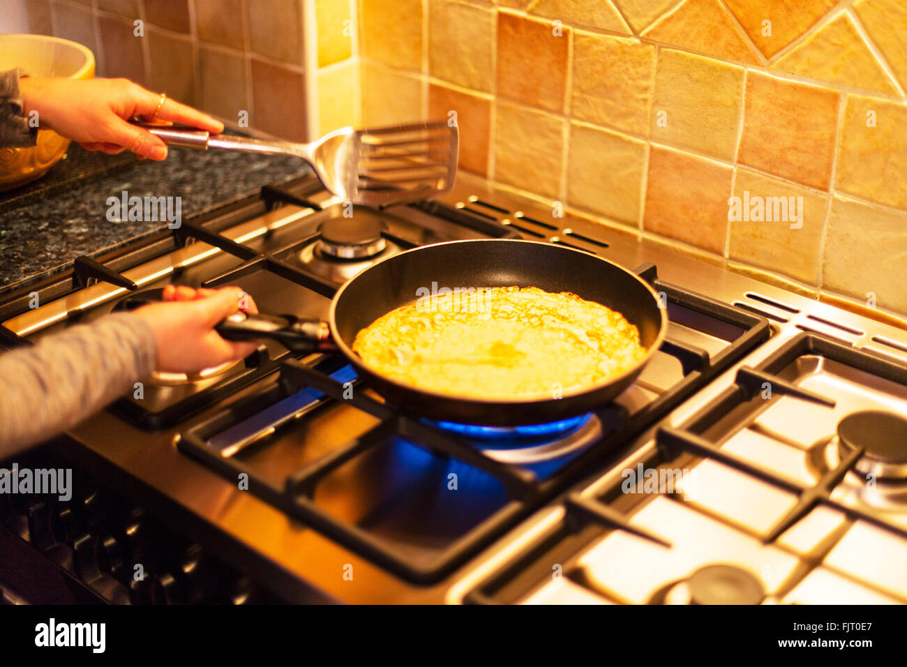 Making pancakes pancake day cooking on gas hob frying pan woman cook Stock Photo