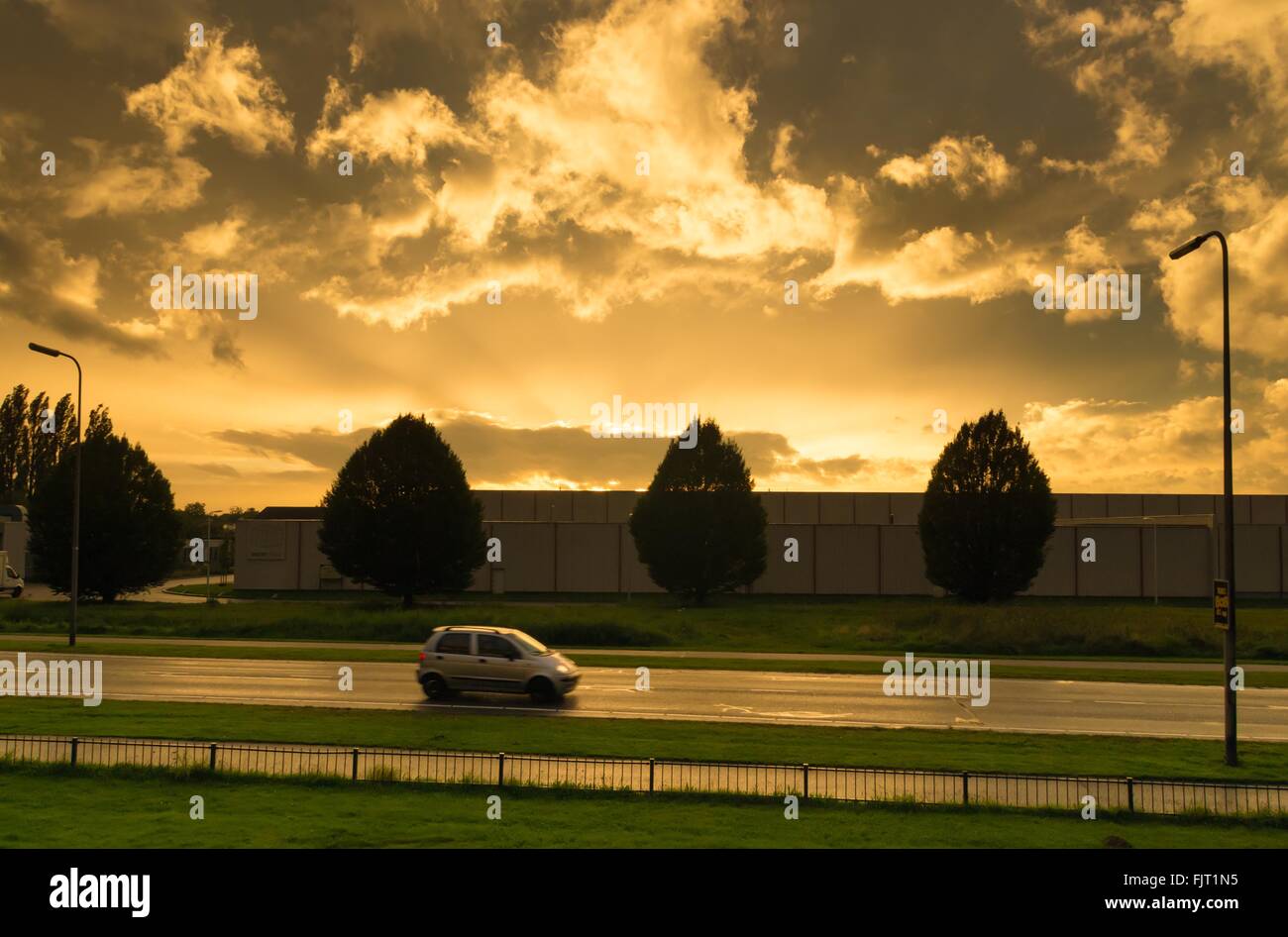 car passing by on a background of some nice copper colored clouds Stock Photo
