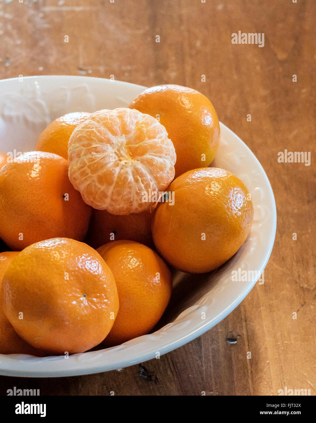 Mandarin oranges, Citrus reticulata, with one peeled in a white bowl Stock Photo Alamy