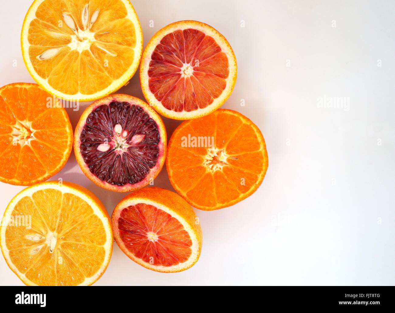 Ruby red blood oranges, navel oranges, and clementines cut in half on a