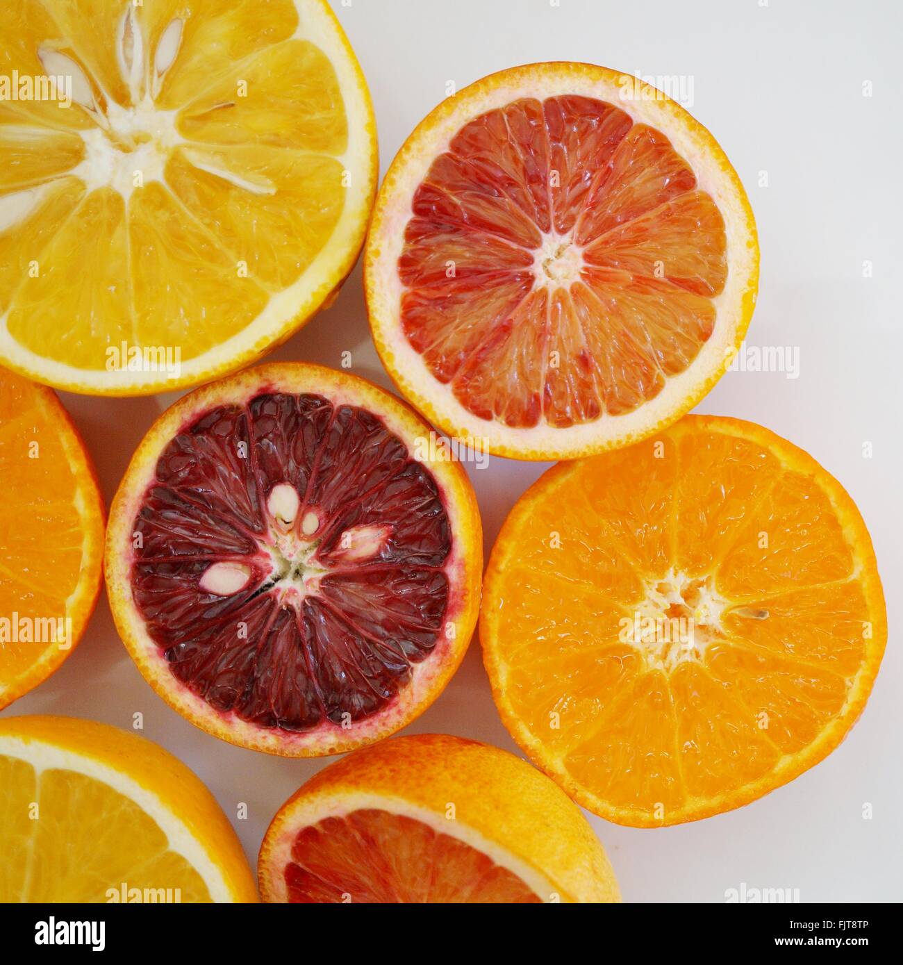 Ruby red blood oranges, navel oranges, and clementines cut in half on a