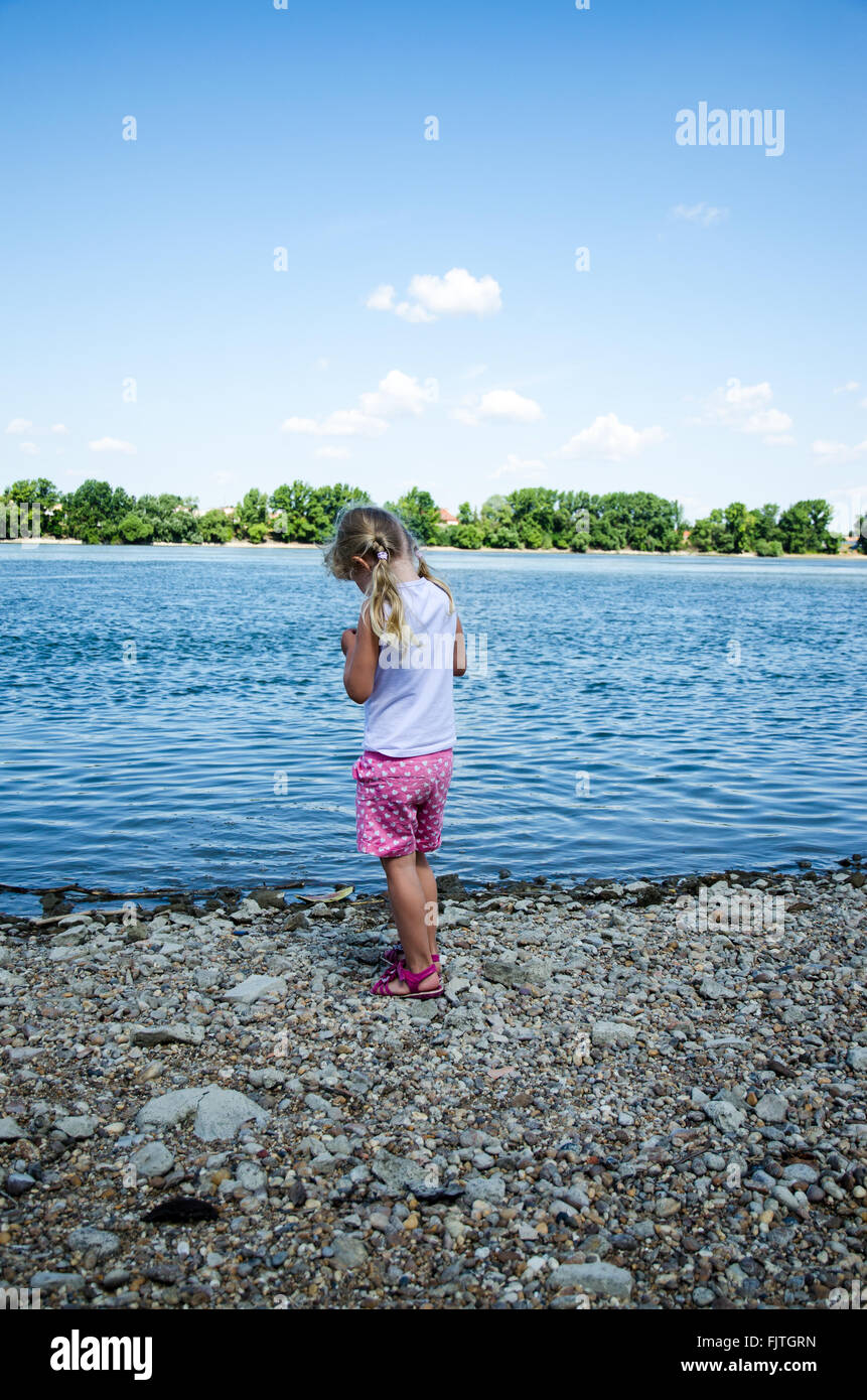 little girl  alone in the strand by the blue river back view Stock Photo