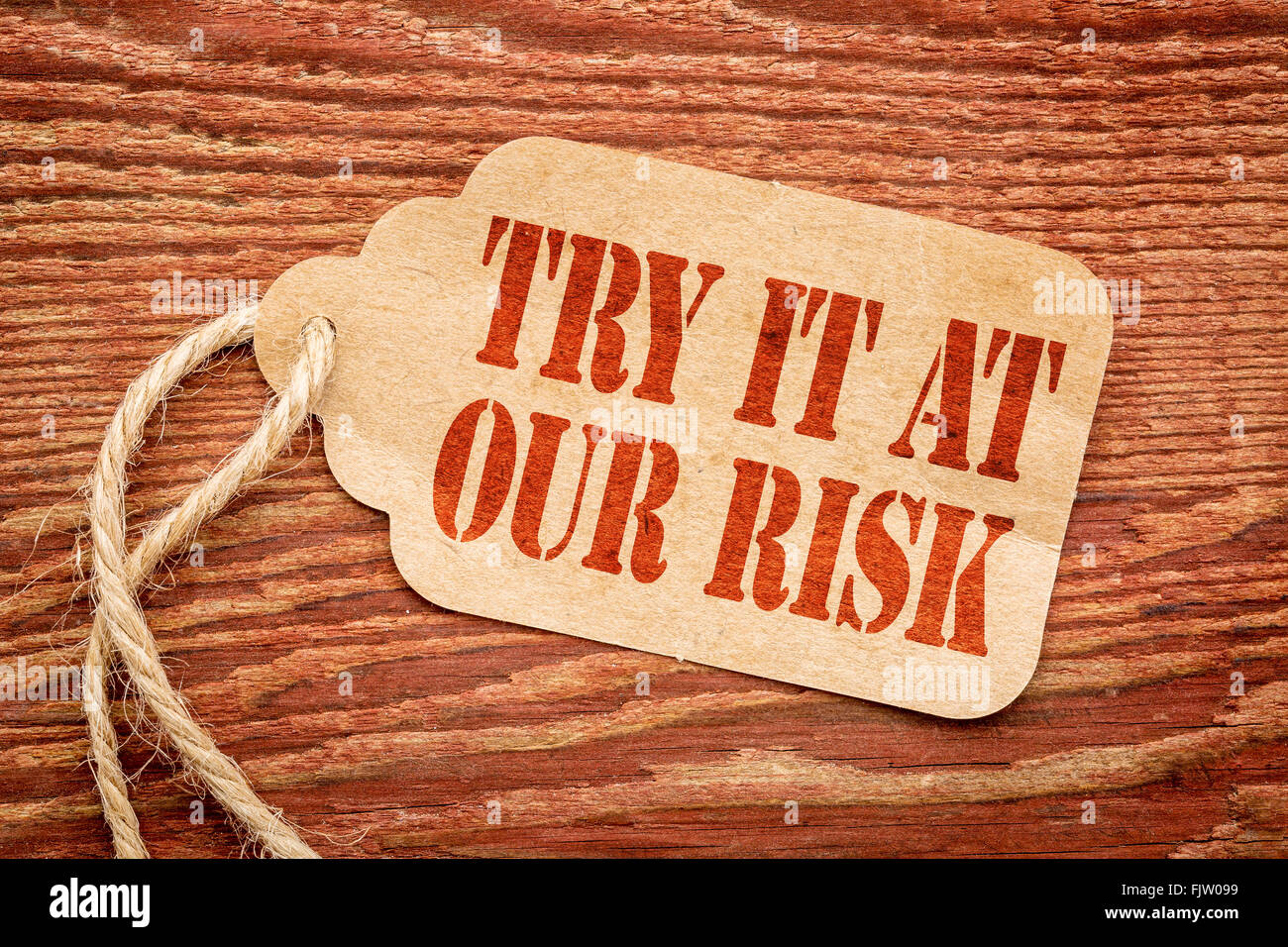 Try it at our risk - red stencil text on a paper price tag against rustic wood Stock Photo