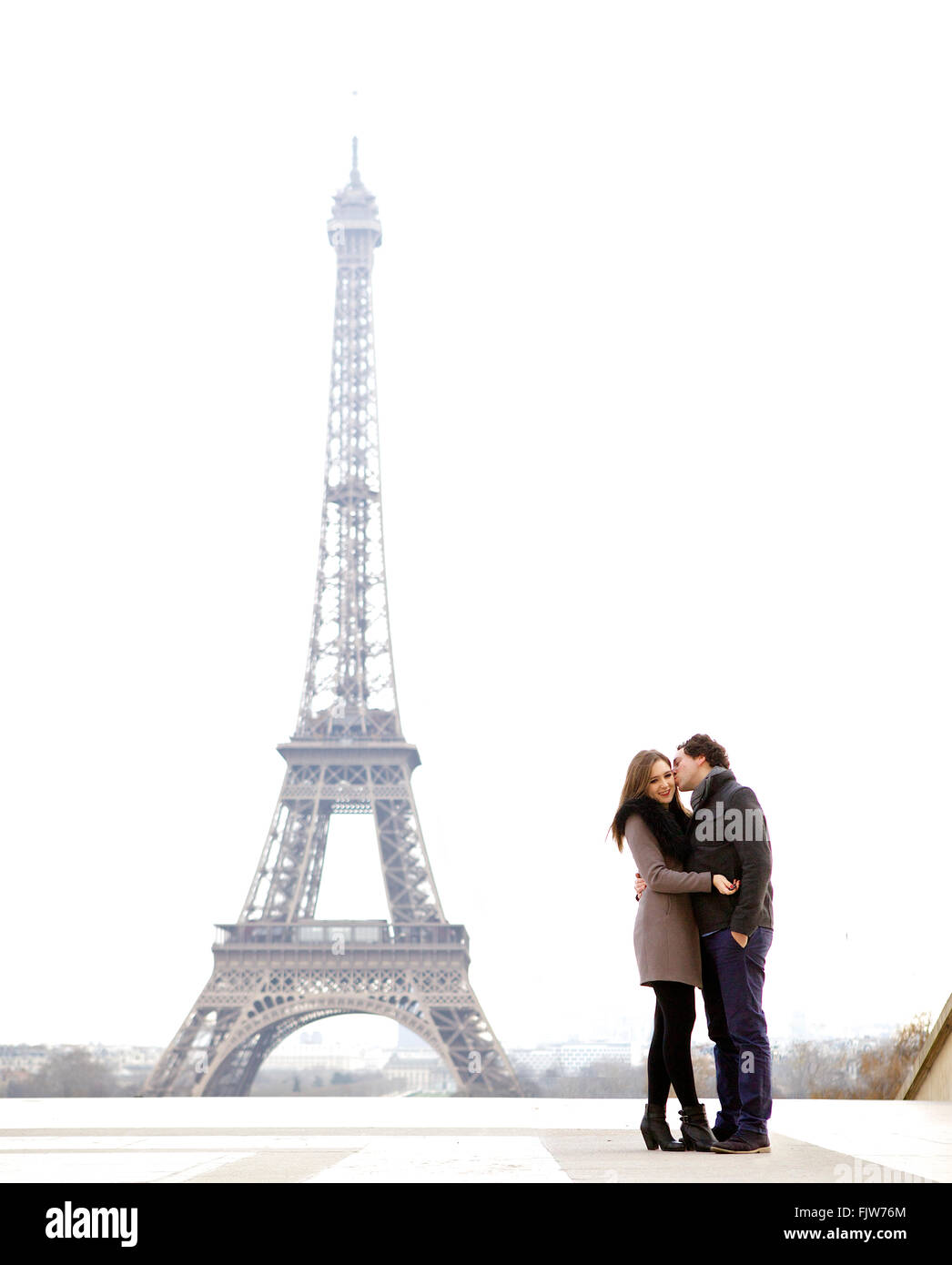 Young and in love brunette couple in front of Eiffel tower, Paris, at Trocadero overlooking the city during the day Stock Photo