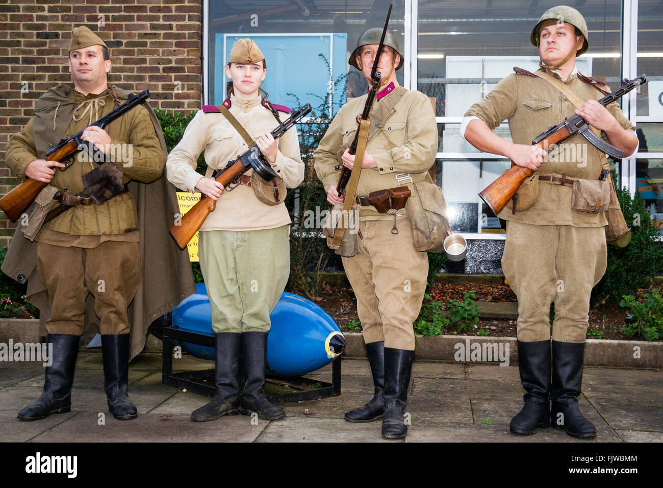 World War two Re-enactment. Four Russian soldiers standing facing viewer, posing, three men, one woman holding rifles and burp-gun, PPSh-41. Stock Photo