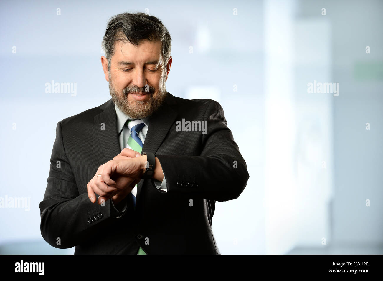 Portrait of Hispanic businessman using smart watch inside office building Stock Photo