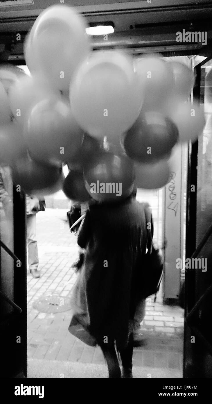 Rear View Of Woman Holding Balloons While Getting Down From Bus Stock