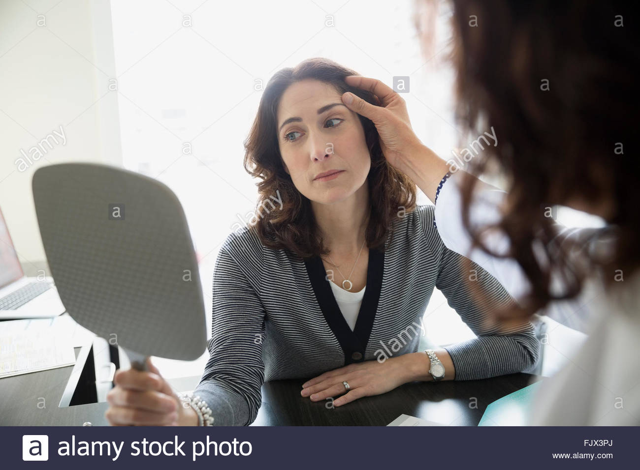 Plastic surgeon consulting female patient mirror doctors office Stock Photo Alamy