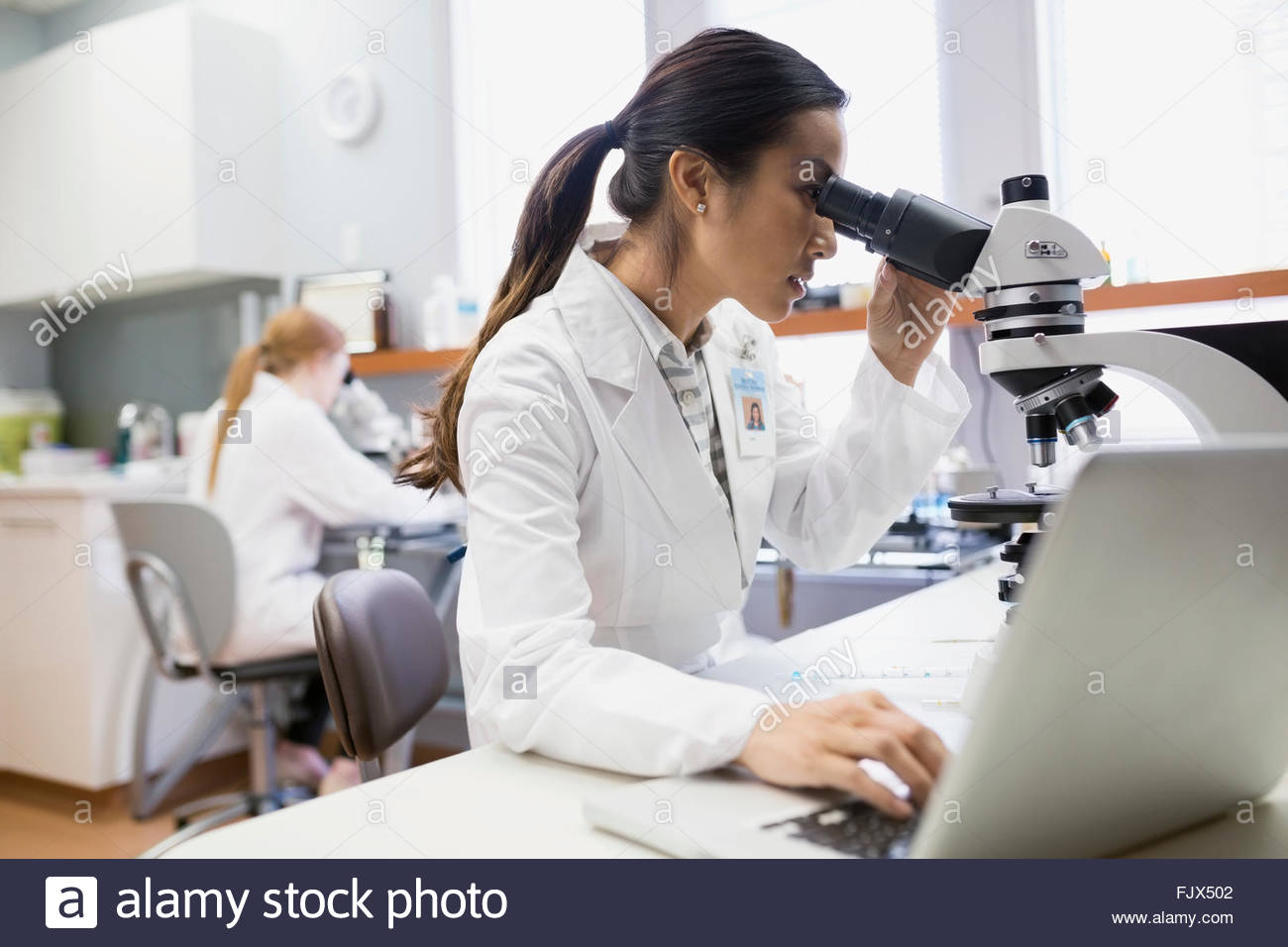 Medical scientist using microscope near laptop in laboratory Stock Photo Alamy