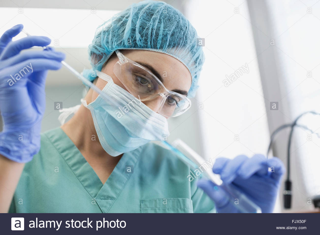Focused female medical technician using pipette in laboratory Stock Photo