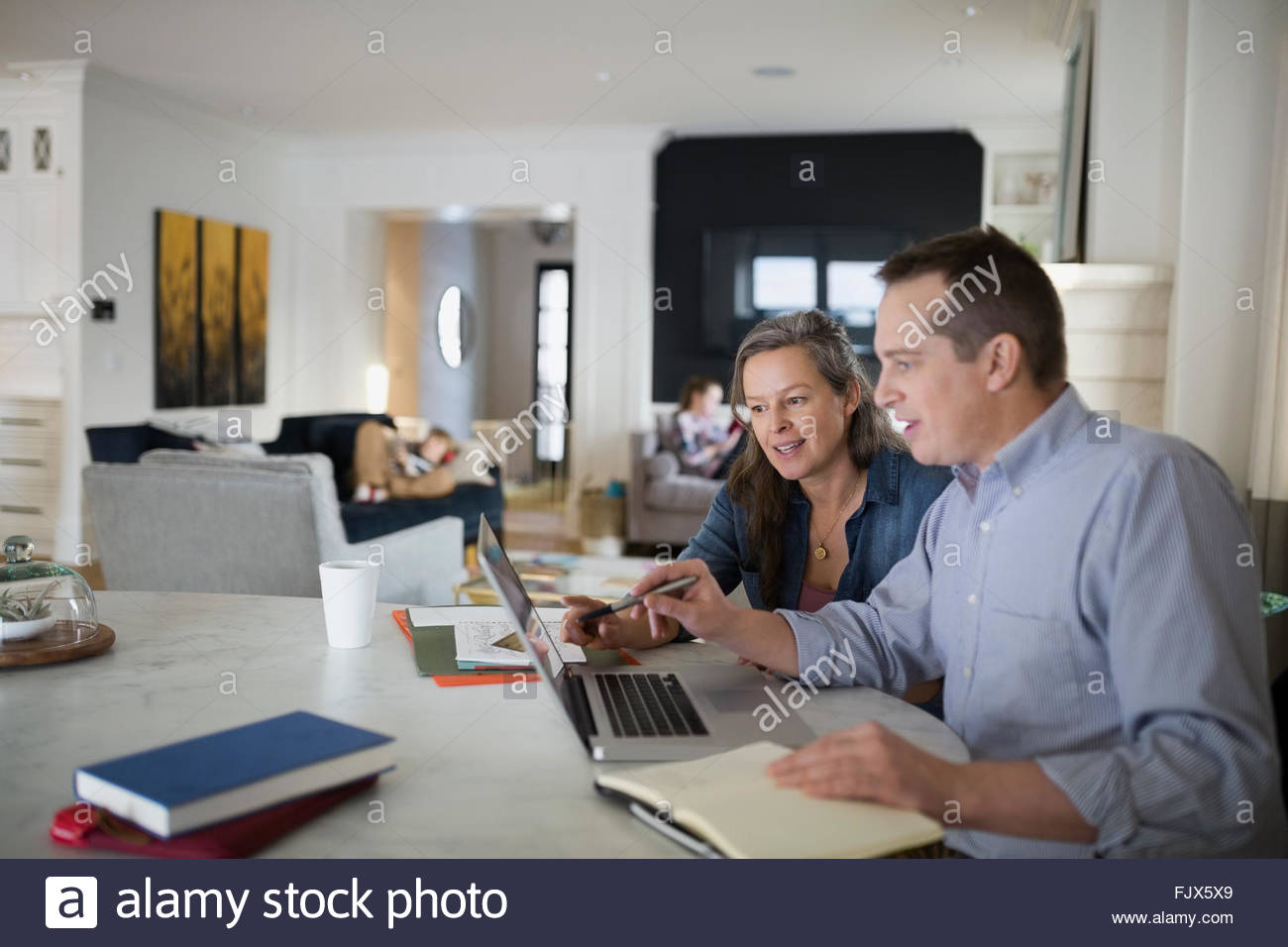 Couple using laptop at kitchen table Stock Photo