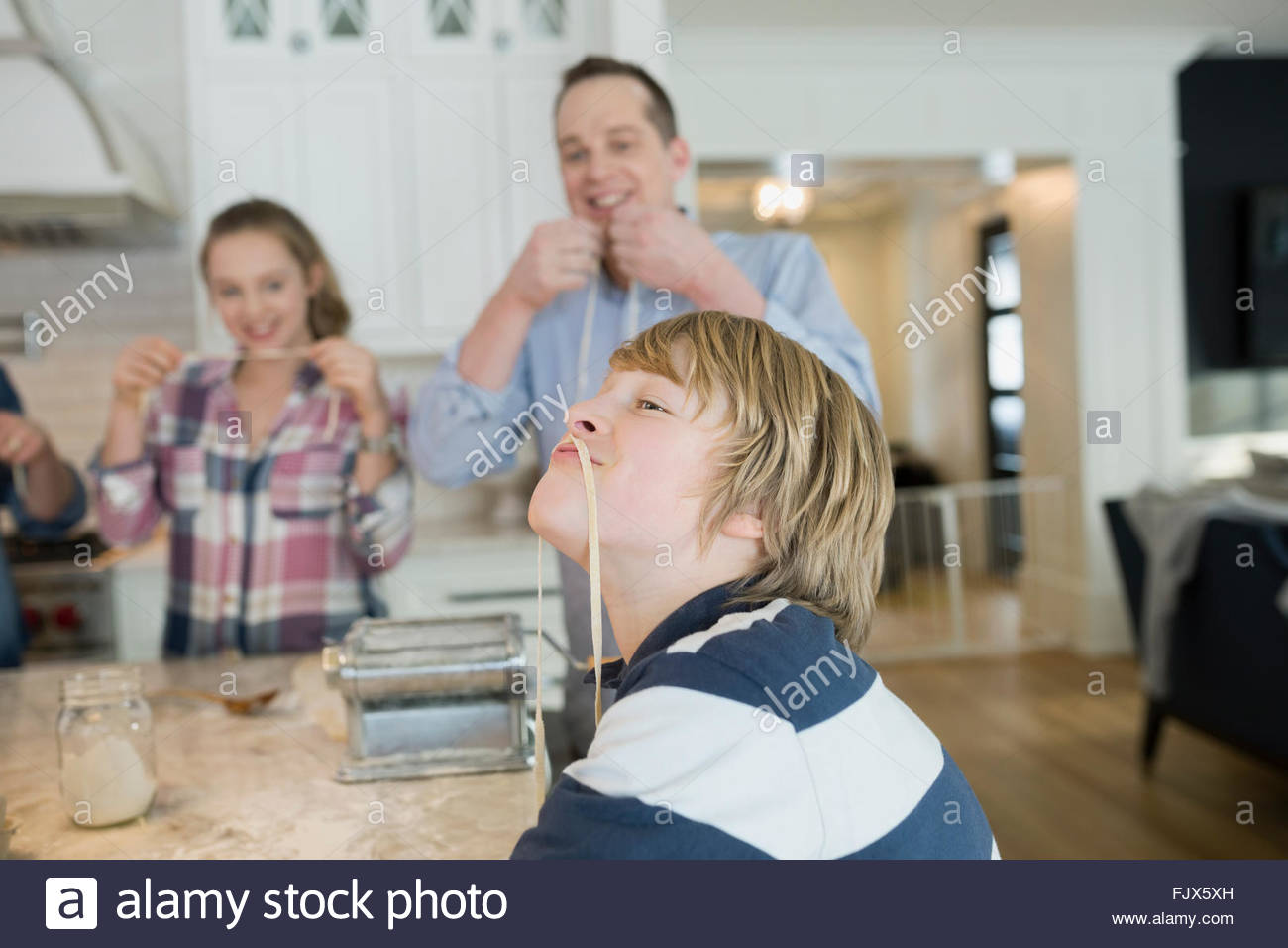 Playful boy with long noodle mustache in kitchen Stock Photo