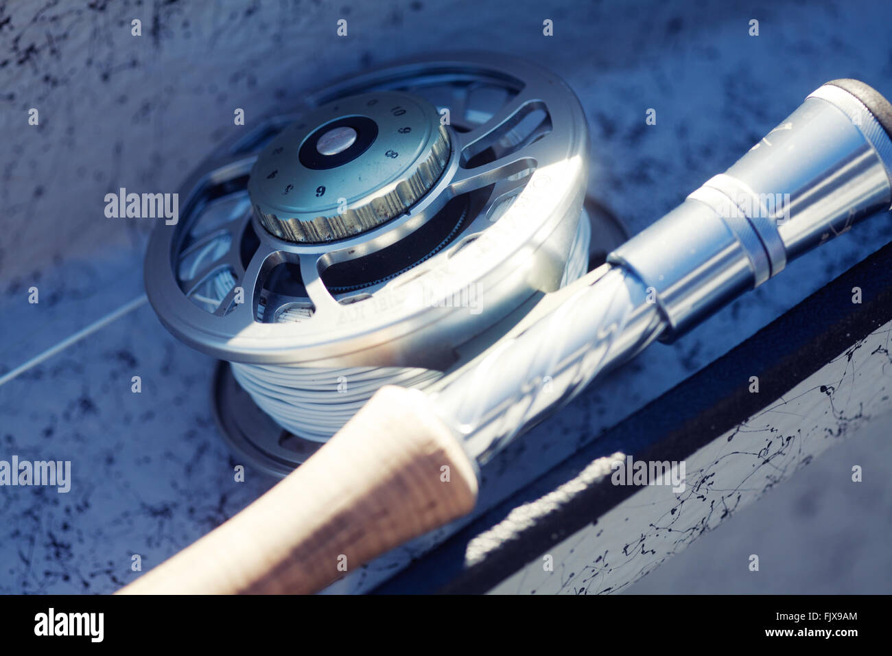 Close up of a fly fishing reel resting on the side of a boat Stock Photo