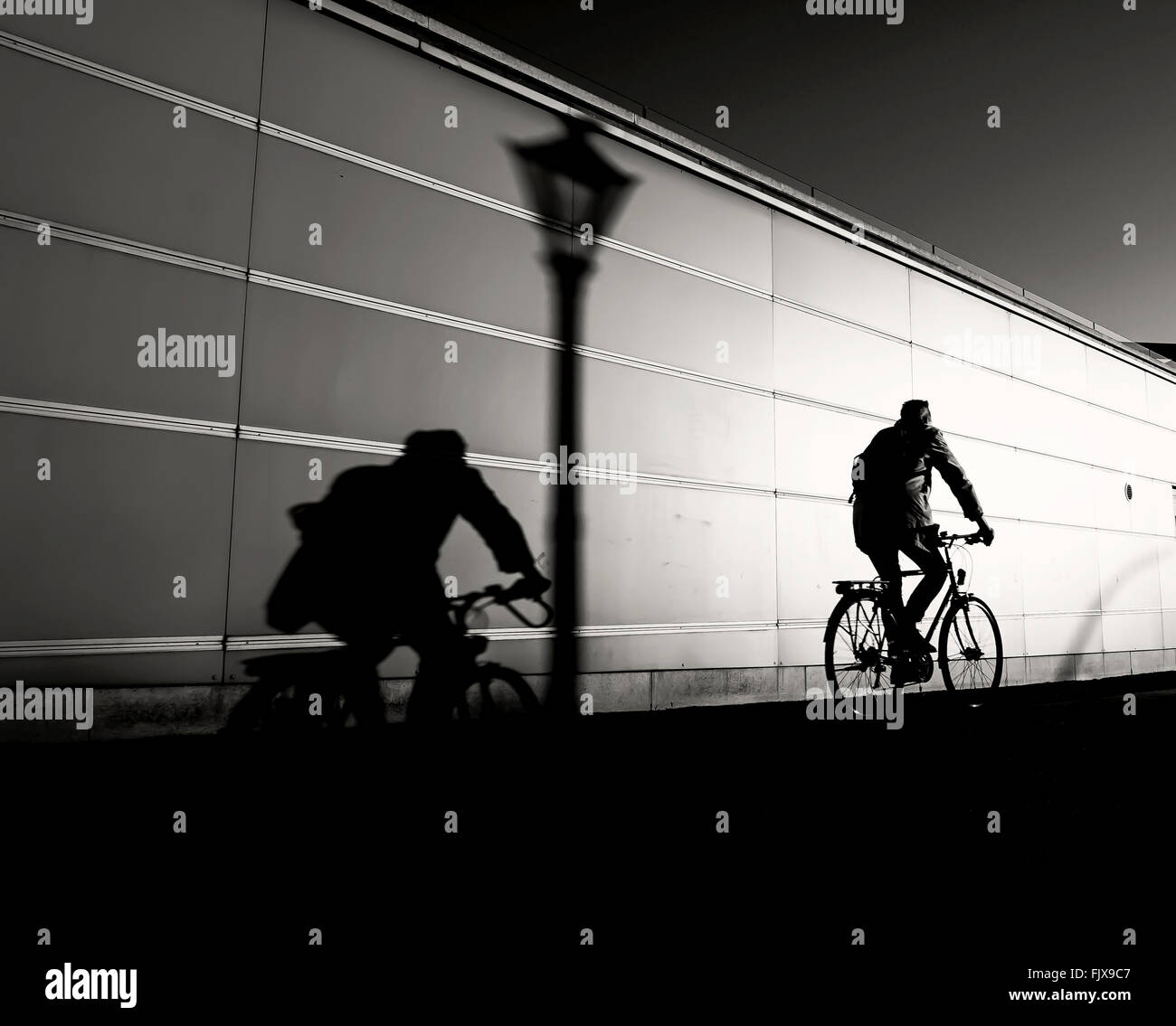 Man Riding Bicycle On Road By Wall Stock Photo