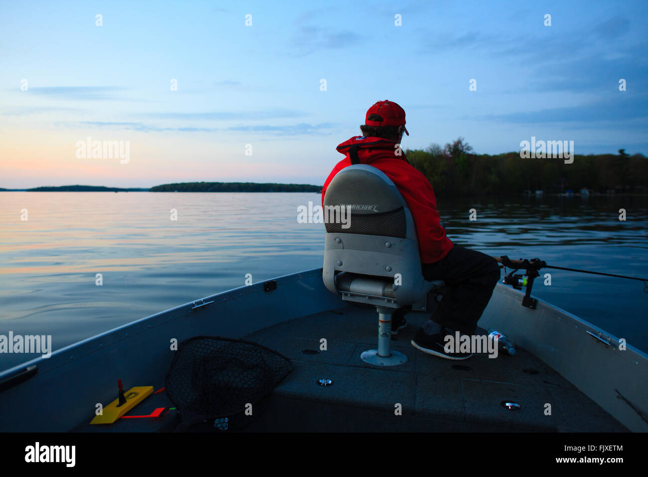 Man fishing off of bow of a boat during the evening Stock Photo