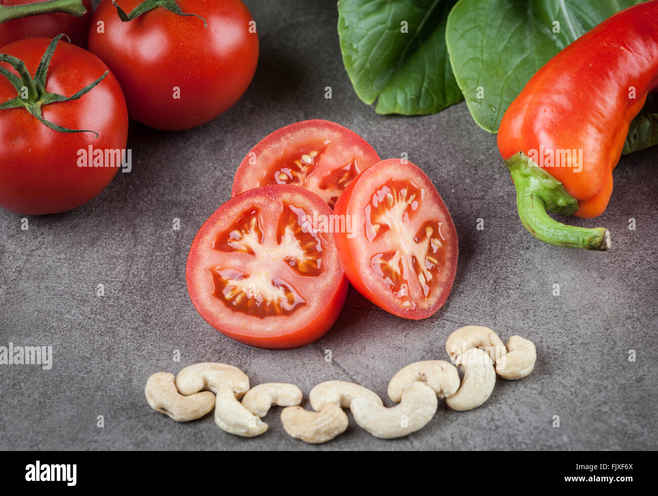 Sliced tomatoes, cashews and sweet chilli on textured background. Stock Photo
