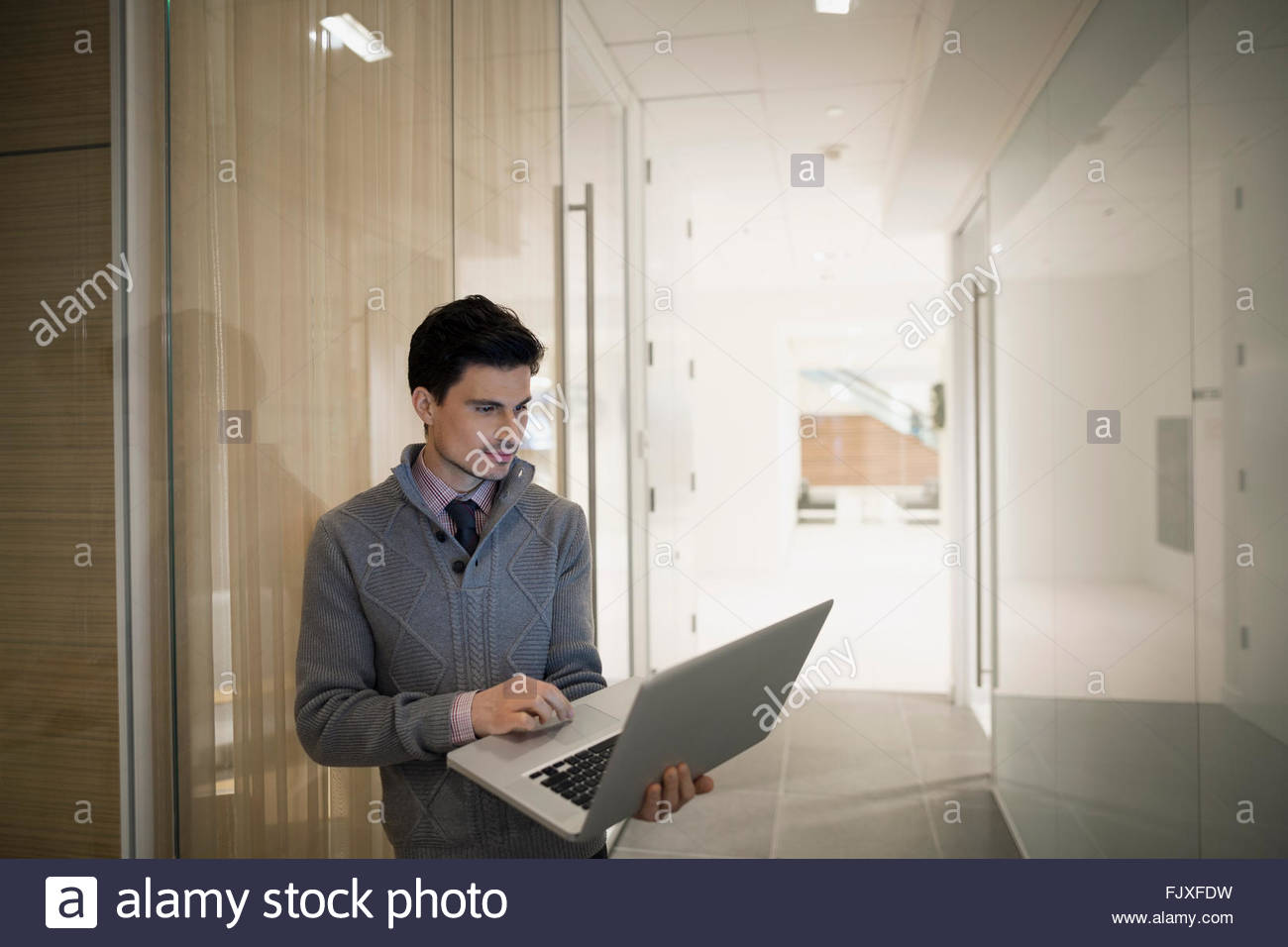 Businessman using laptop in office corridor Stock Photo
