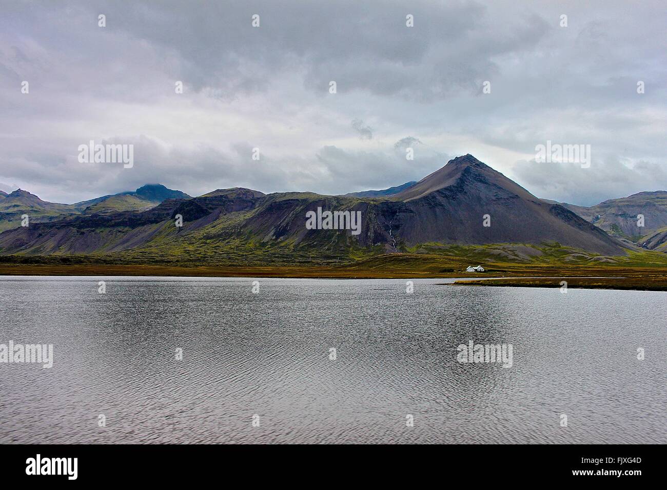 Scenic View Of Calm Lake By Mountains Against Cloudy Sky Stock Photo