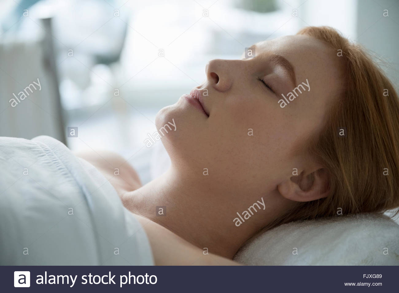 Serene woman laying massage table with eyes closed Stock Photo