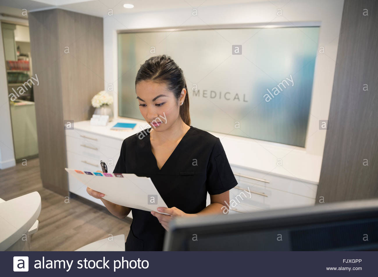 Nurse reviewing medical chart at clinic reception Stock Photo Alamy