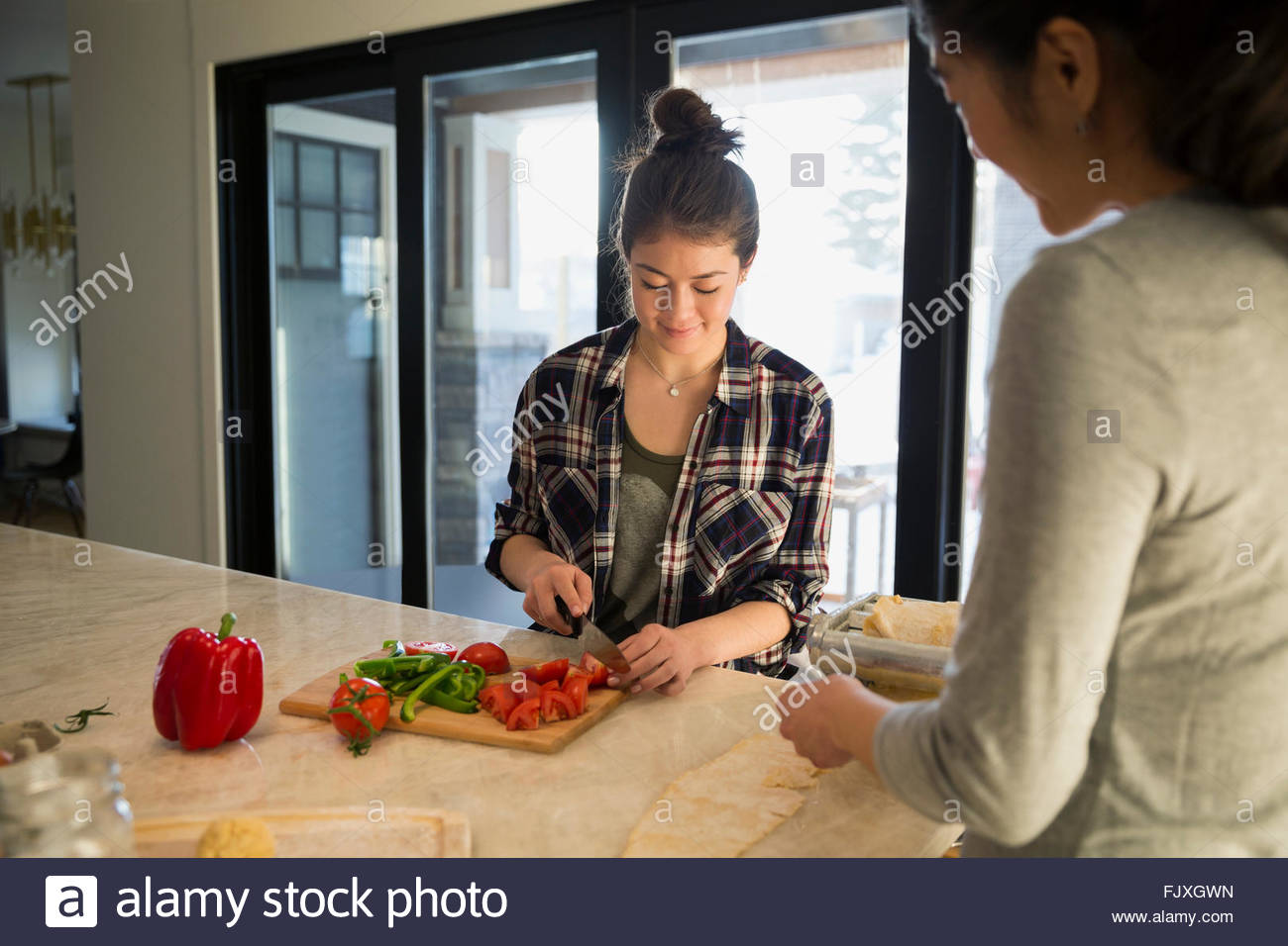 Mother and teenage daughter slicing vegetables in kitchen Stock Photo