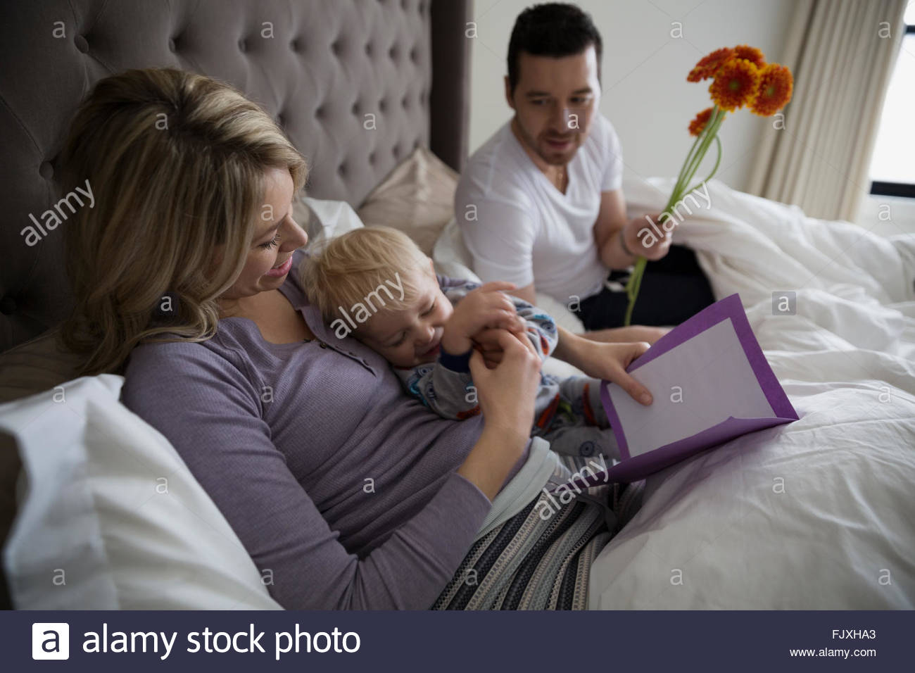 son giving mother mothers day card bed 2-3 years Stock Photo