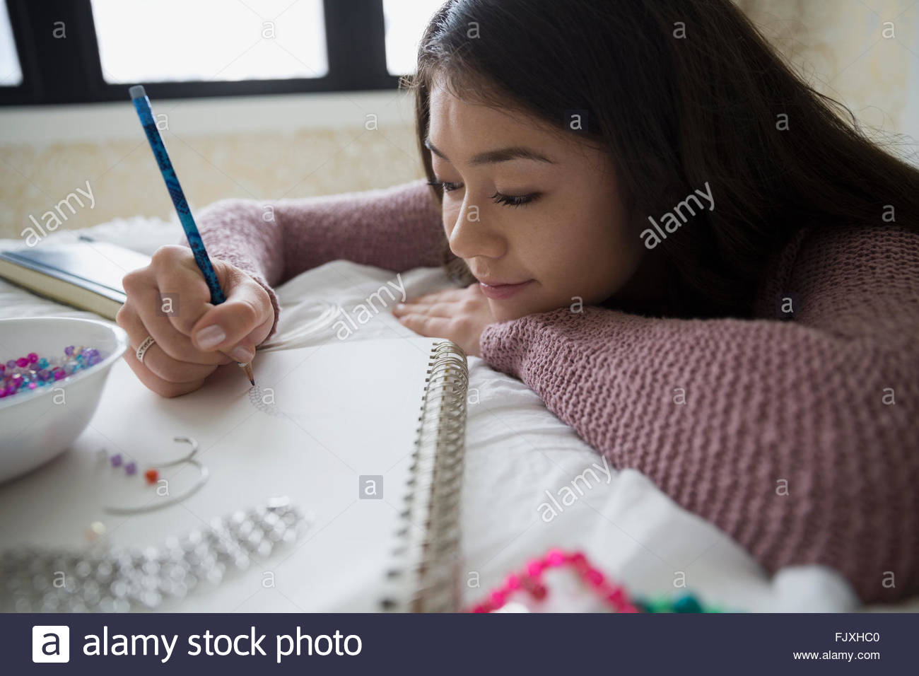 Teenage girl sketching and making jewelry Stock Photo