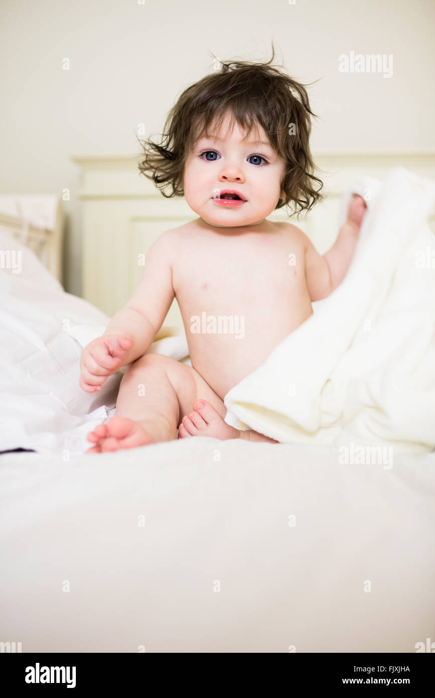 Cute baby sitting on a bed Stock Photo