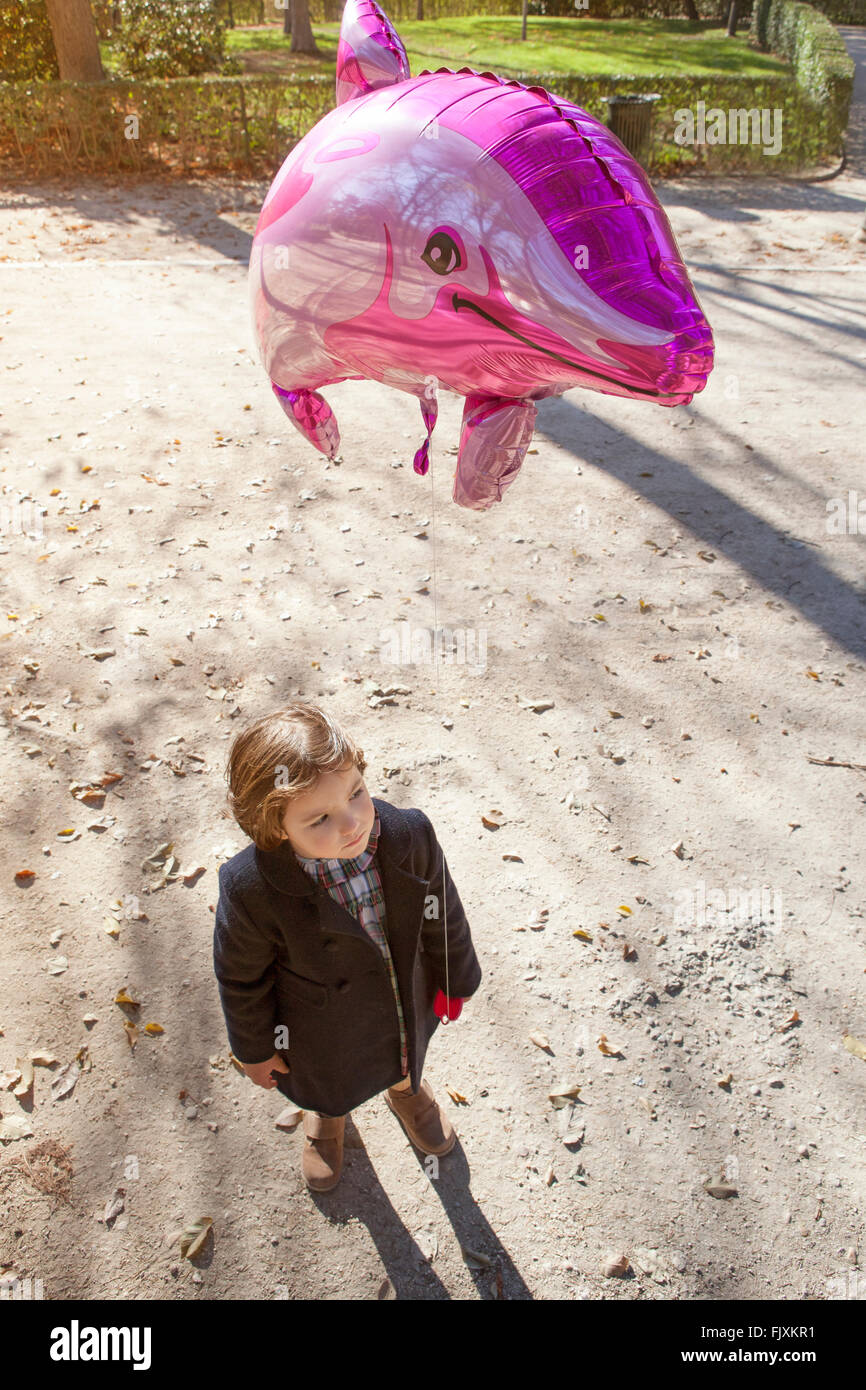 Happy little girl holding a big balloon dolphin shaped in a park Stock Photo