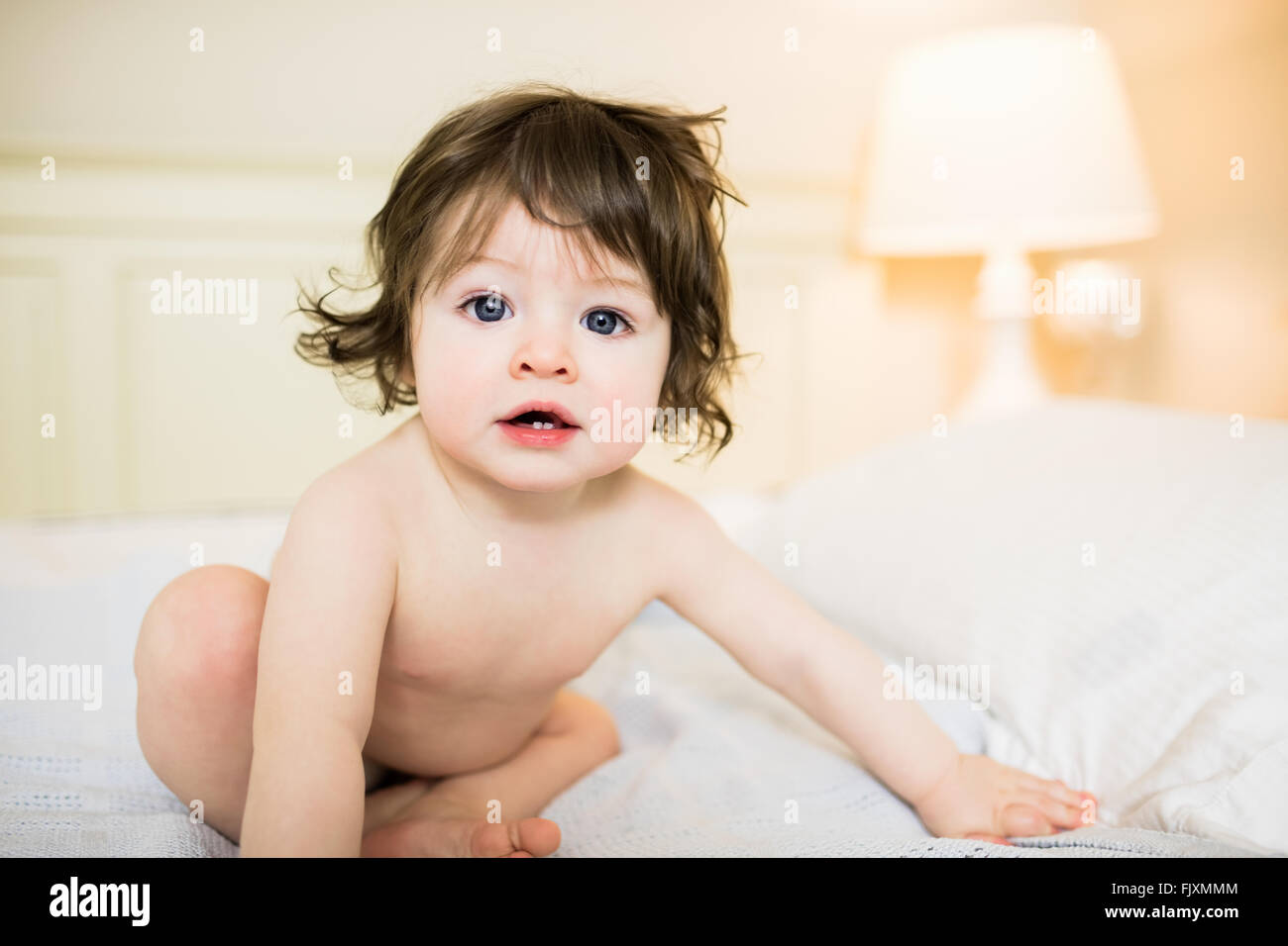 Cute baby sitting on the bed Stock Photo