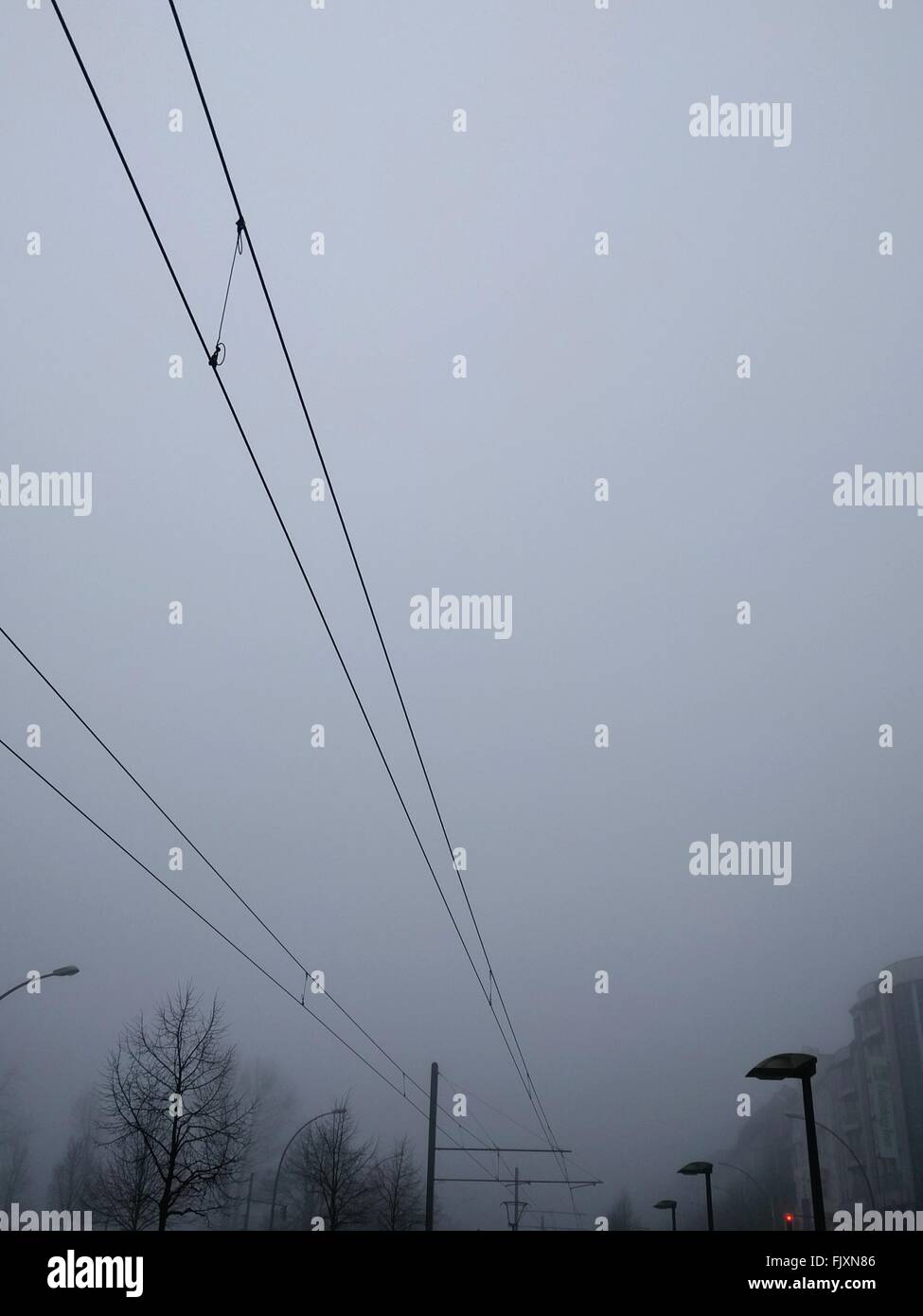 Low Angle View Of Power Lines Against Sky In Foggy Weather Stock Photo