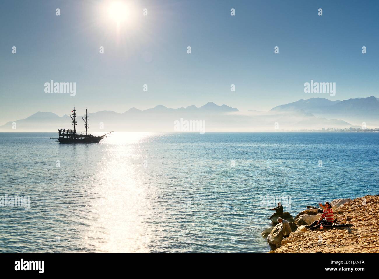 Antalya, Turkey. Looking west from entrance of Kaleici harbour.  Fishermen and tourist sightseeing boat Stock Photo