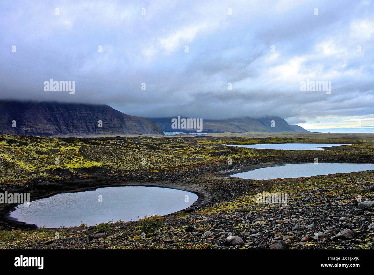 Scenic View Of Ponds On Field Against Cloudy Sky Stock Photo