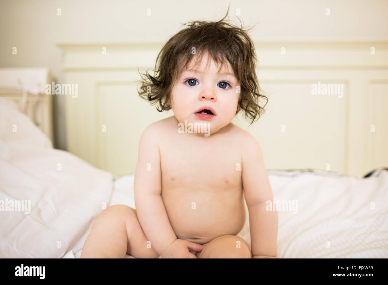 Cute baby sitting on a bed Stock Photo