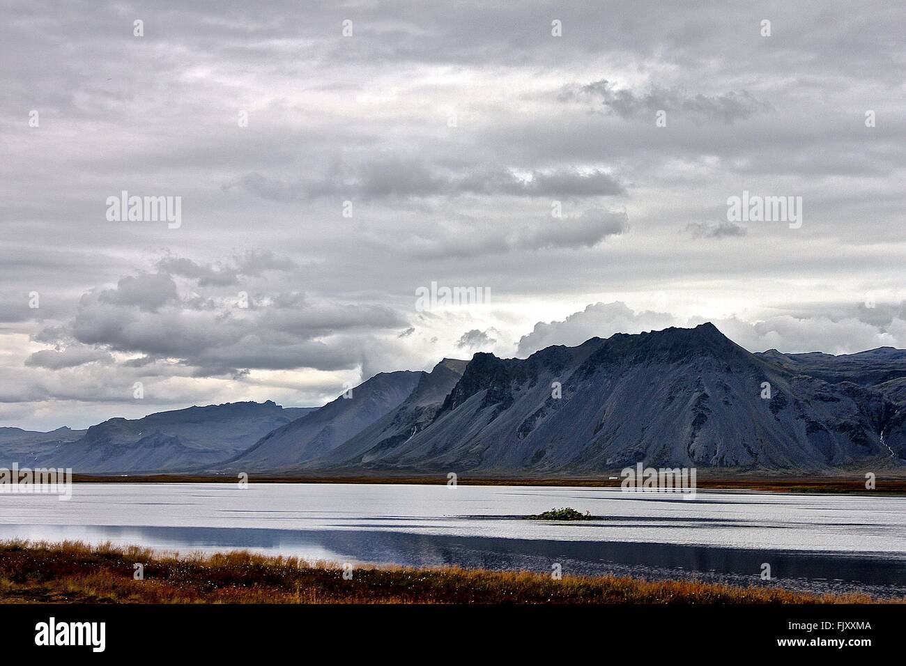 Idyllic Shot Of River And Mountains Against Cloudy Sky Stock Photo