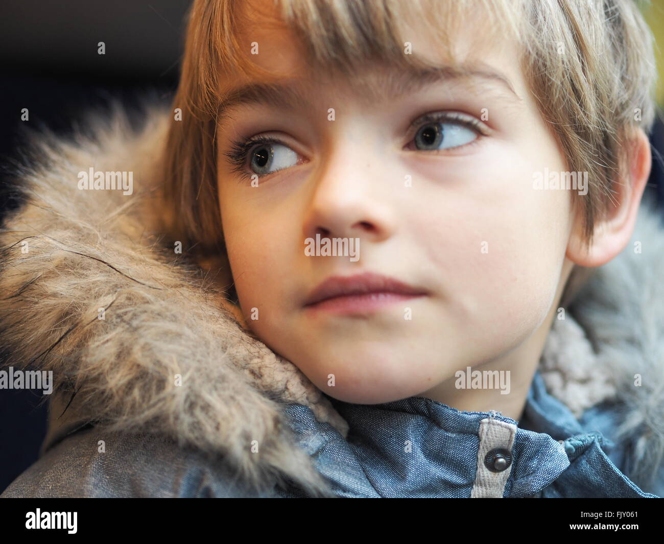 Close-Up Of Boy Wearing Fur Jacket In Car Stock Photo